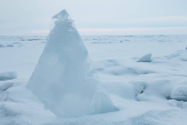 Transparent blue ice floes piled in ice hummocks against a blue sky on a sunny day. Unusual winter landscape of the frozen lake Baikal. Natural cold background. Siberia, Russia.