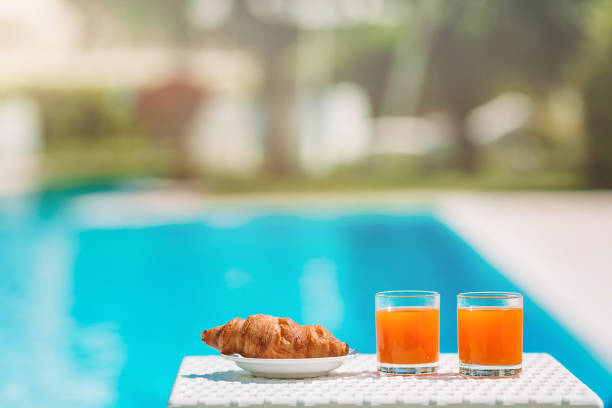 istock Delicious breakfast lemon, coffee, croissant by the pool 1220167201