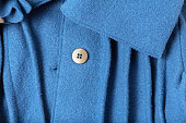 Fragment of a button and collar with folds of a fashionable blue woolen coat