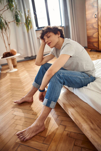 istock Attractive young man sitting on bed at home 1220168829