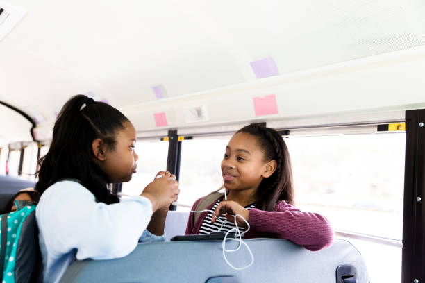 istock Girls share earbuds while standing in school bus 1220169319
