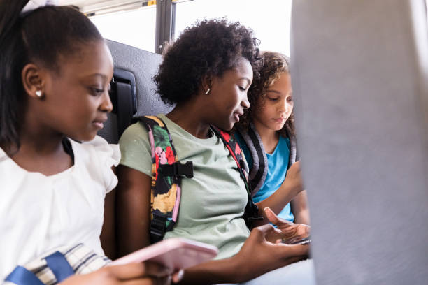istock Riding on bus, diverse female students play on smart phones 1220169374