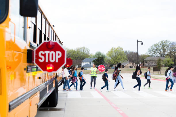 istock Students use crosswalk; bus has warning sign out 1220169432