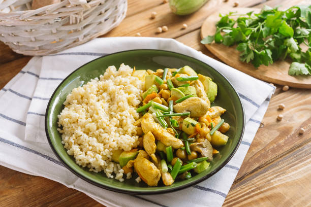 Green plate with chopped chicken with bulgur on the side dish, chickpeas and oyster mushrooms. The dish is sprinkled with chopped scallion. stock photo