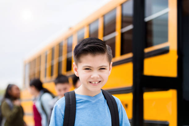 istock Young boy stands by school bus before boarding 1220169469