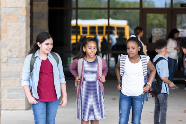 istock Happy school girls leave school building 1220169599