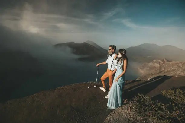 Photo of Man and woman in protective masks stand on the edge of the crater