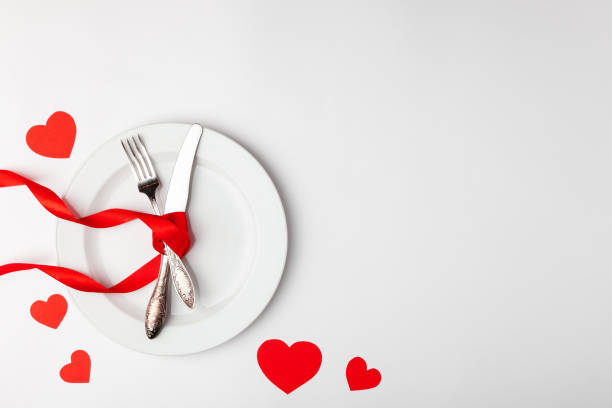 istock Romantic festive table setting on white background. Valentines day card template. Red ribbon, plate, silverware, vintage fork, knife. Concept anniversary, birthday, place for text, copyspace, top view 1220173071