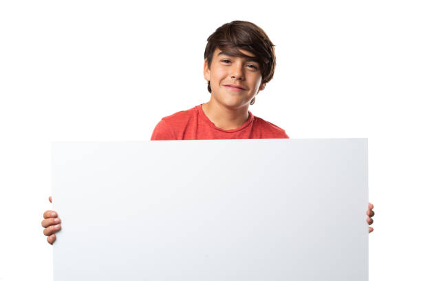istock Cute latinx hispanic boy smiling, holding a blank sign, on white background 1220173499