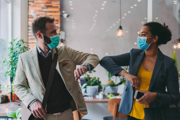 Business people greeting during COVID-19 pandemic, elbow bump Colleagues in the office practicing alternative greeting to avoid handshakes during COVID-19 pandemic viral infection photos stock pictures, royalty-free photos & images
