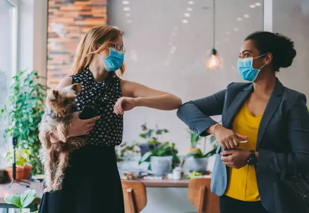 Coworkers in the office with alternative greeting for safety and protection during COVID-19