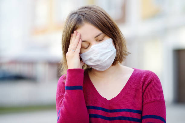Young woman wearing a protective mask in public place. Safety during COVID-19 outbreak. Young woman wearing a protective mask in public place. Safety during COVID-19 outbreak. Pandemic of coronavirus. symptom photos stock pictures, royalty-free photos & images