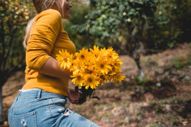 istock Young woman carrying yellow flowers 1220180426