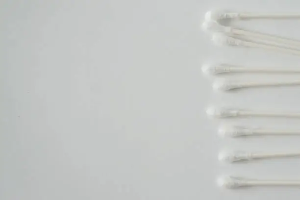 Q tip, or cotton bud swab top view on horizontal white background with blank empty space for copy or text; Features best health care hygiene practices to clean ear.
