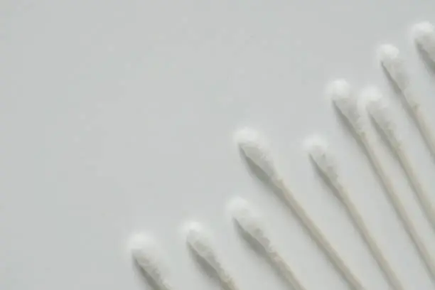 Q tip, or cotton bud swab top view on horizontal white background with blank empty space for copy or text; Features best health care hygiene practices to clean ear.