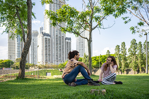 Two men sitting in a park together, talking and relaxing