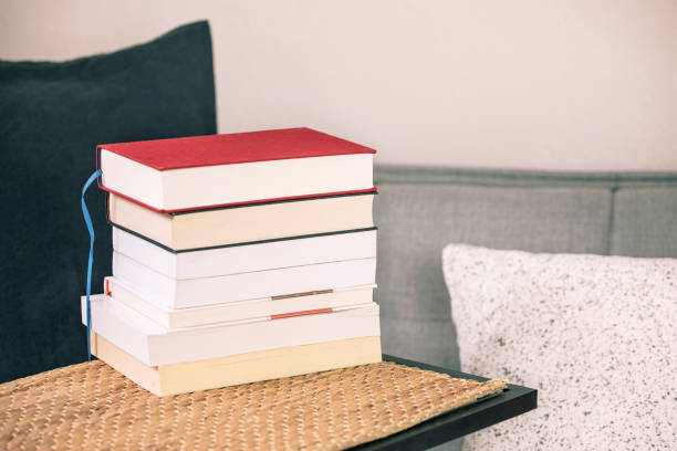 istock Book stack on the table with cozy sofa, cushions and pillows. Reading books, study at home, learning. 1220185006