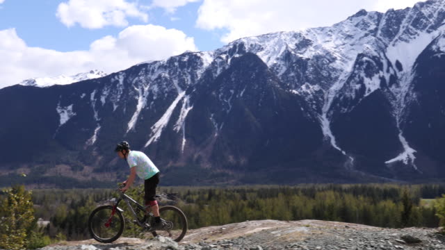 Young man mountain bikes along mountain ridge crest