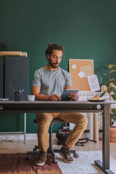 istock Working from Home: Young Designer Using a Digital Tablet at His Improvised Home Office 1220189237