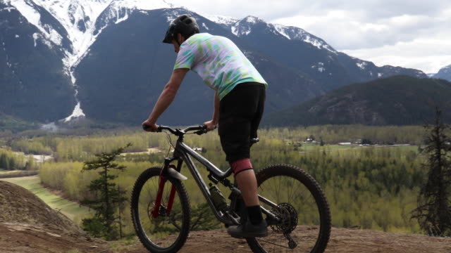 Young man mountain bikes along mountain ridge crest