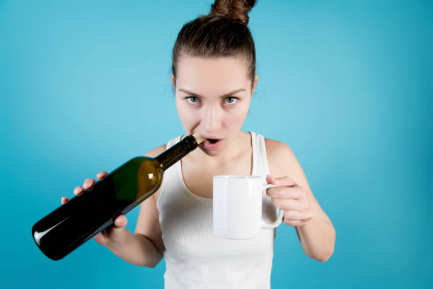 a young woman opens a bottle of wine with her teeth pulling out a cork - cork tops imagens e fotografias de stock
