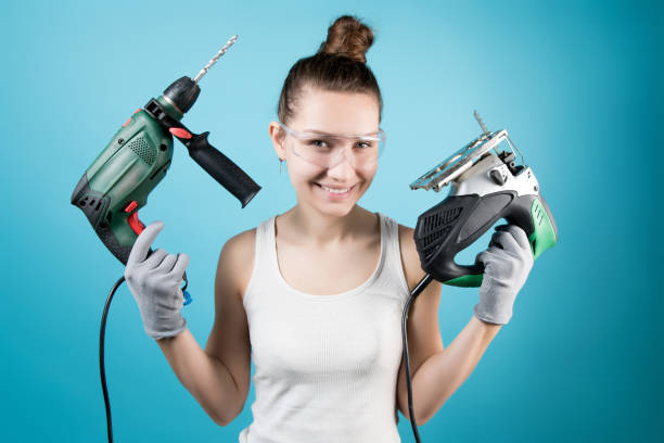 istock A cunningly smiling girl and power tools in her hands - a jigsaw and a drill 1220195581