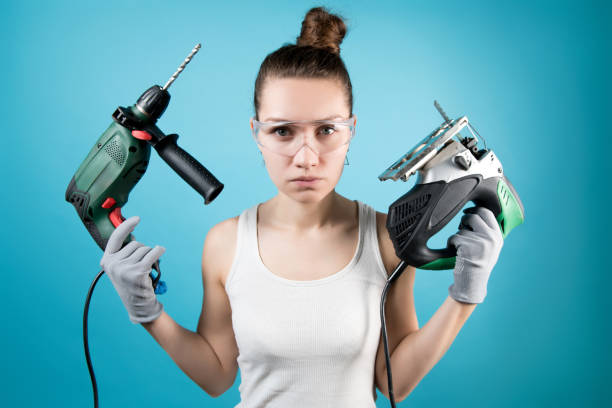 istock girl holds a drill and an electric jigsaw in her hands. 1220195588