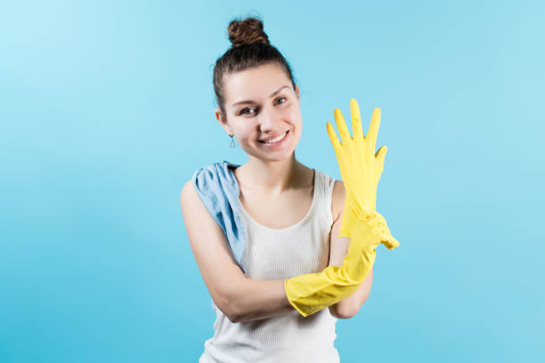 istock Smiling girl pulls a yellow household glove on her hand 1220195629