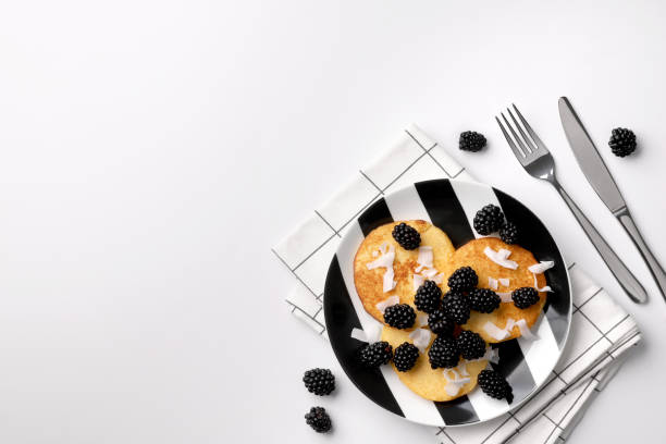 Pancakes made of coconut flour with blackberries and coconut chips on white table. Homemade healthy breakfast.