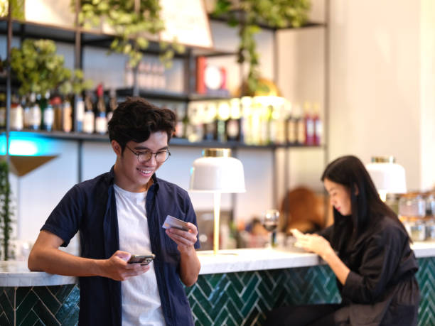 young man paying bills using card and mobile phone