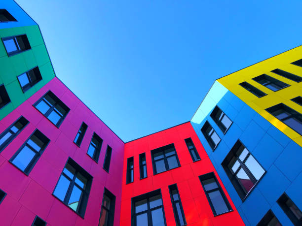 Multi-colored facades of the school with black window frames. Look up from the blue sky