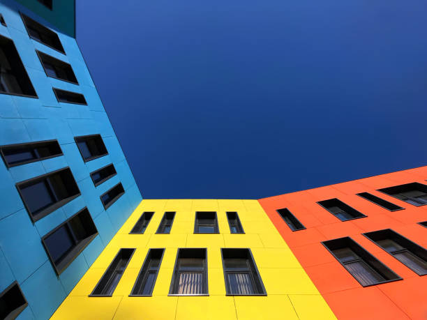 Multi-colored bright facades of the school with black window frames. Look up from the blue sky