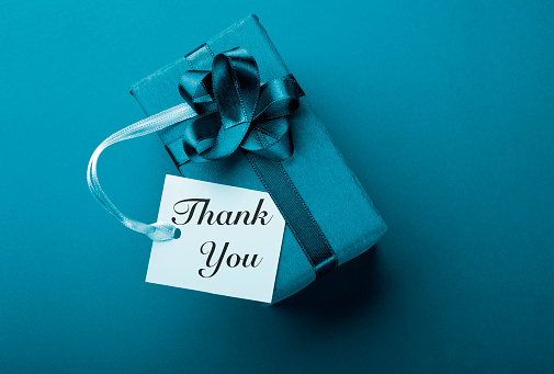 white gift box with Thank You note on blue background. Horizontal composition with copy space. Shopping and gift concept.