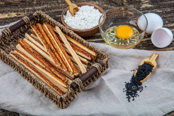 Wholemeal grissini, crispy straw with black seed seeds on a wooden background.
