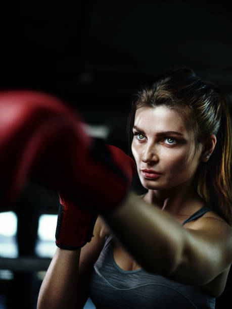 istock Portrait of determined beautiful female boxer in red gloves practicing boxing punches or fighting in ring 1220199607