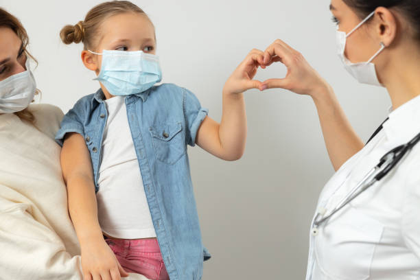 mère caucasienne et son gosse utilisant des masques médicaux dans la clinique - doctor child baby healthcare and medicine photos et images de collection