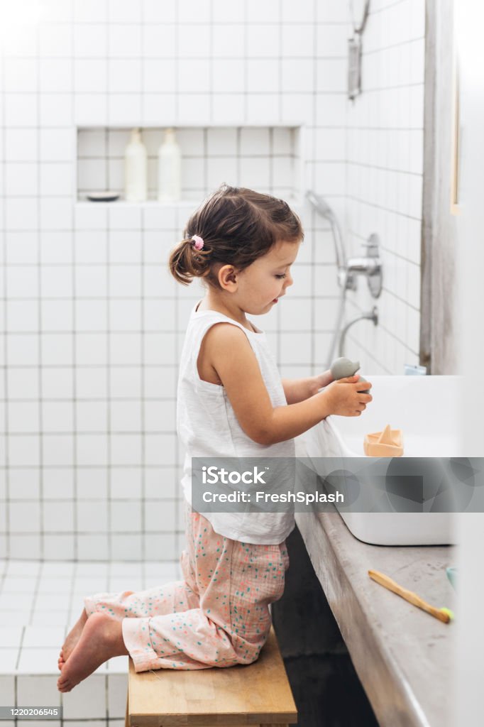 Happy Girl in Pajamas Playing With Rubber Toys in the Bathroom Sink Adorable Caucasian child playing in the bathroom. Child Stock Photo