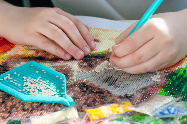 Collecting diamond mosaic. Colored crystals. Needlework. Creation. CloseUp.