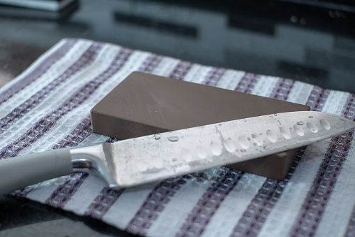 Afilado de cuchillos en Whetstone mojado, cuchillo de chef Santoku de cerca photo