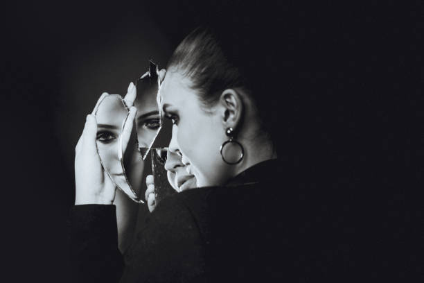 istock Beautiful brunette woman and broken self-image mirror on black 1220210836