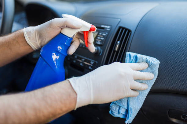 istock Man cleansing car dashboard and spraying with disinfection liquid. 1220210929