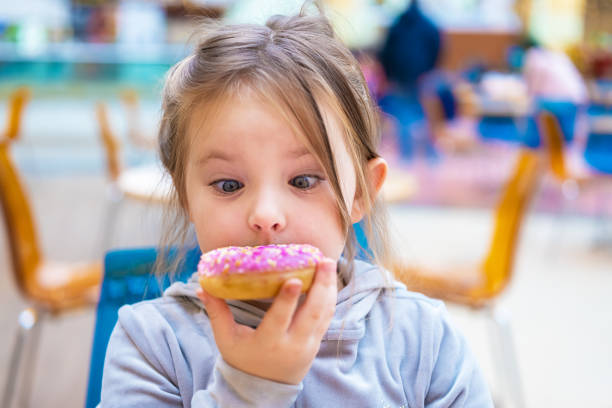 istock Cute girl eating a donut in a cafe. 1220214317