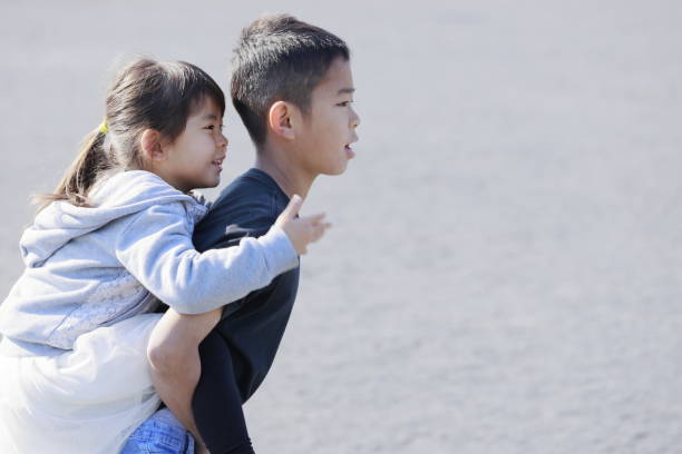 istock Japanese boy carrying his sister in his back (10 years old boy and 5 years old girl) 1220218014