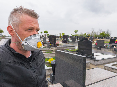 Man standing at large cemetery in times of coronavirus covid19 pandemic.