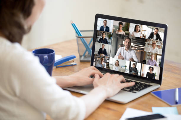 Laptop screen view diverse businesspeople involved at group videocall On laptop screen web cam view diverse age and ethnicity businesspeople taking part at group videocall, view over woman shoulder sit at desk working from home. Distant communication, modern app concept webcam view man stock pictures, royalty-free photos & images