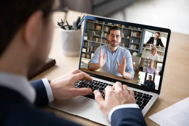 Photo of View over businessman shoulder laptop screen and videocall diverse participants