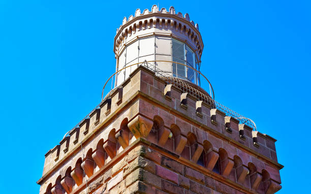 Lighthouse at Atlantic Ocean Bay shore at Sandy Hook. Light house tower is called US Navesink Twin Lights. It is in Highlands in Monmouth County in New Jersey, USA. Blue sky background