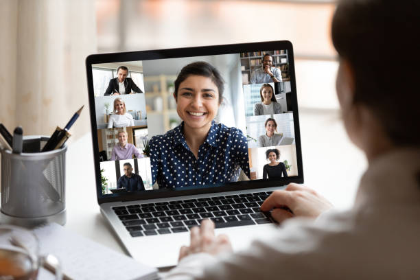 Indian lady lead videocall, pc screen view over woman shoulder Woman sit at desk looking at computer screen where collage of diverse people webcam view. Indian ethnicity young woman lead video call distant chat, group of different mates using videoconference app webcam view man stock pictures, royalty-free photos & images