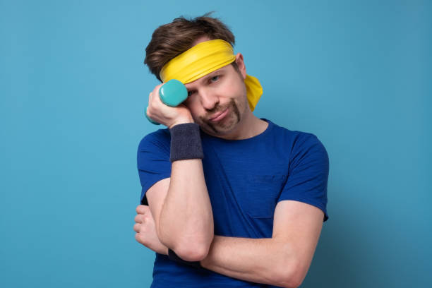 istock Crazy funny man try to lift small blue dambbell 1220228649