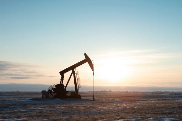 North American  Oil Single pump jack producing oil, sun rising. Image taken from a tripod. crude oil stock pictures, royalty-free photos & images